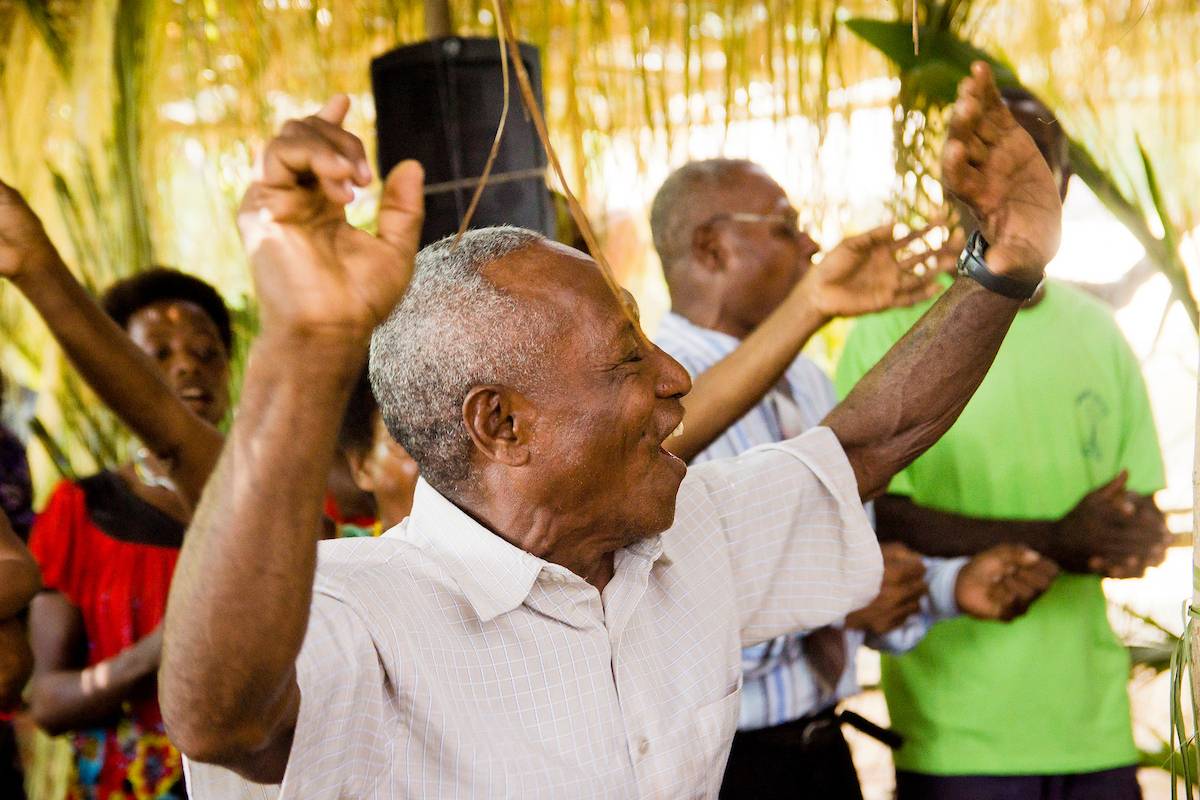 A man holds up both arms as he sings.